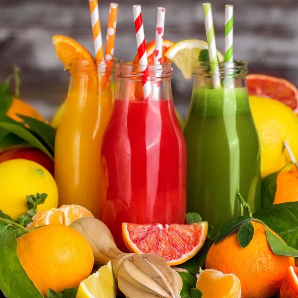Fresh orange, blood orange juice and homemade lemonade in small bottles on old wooden table. Copy space background.